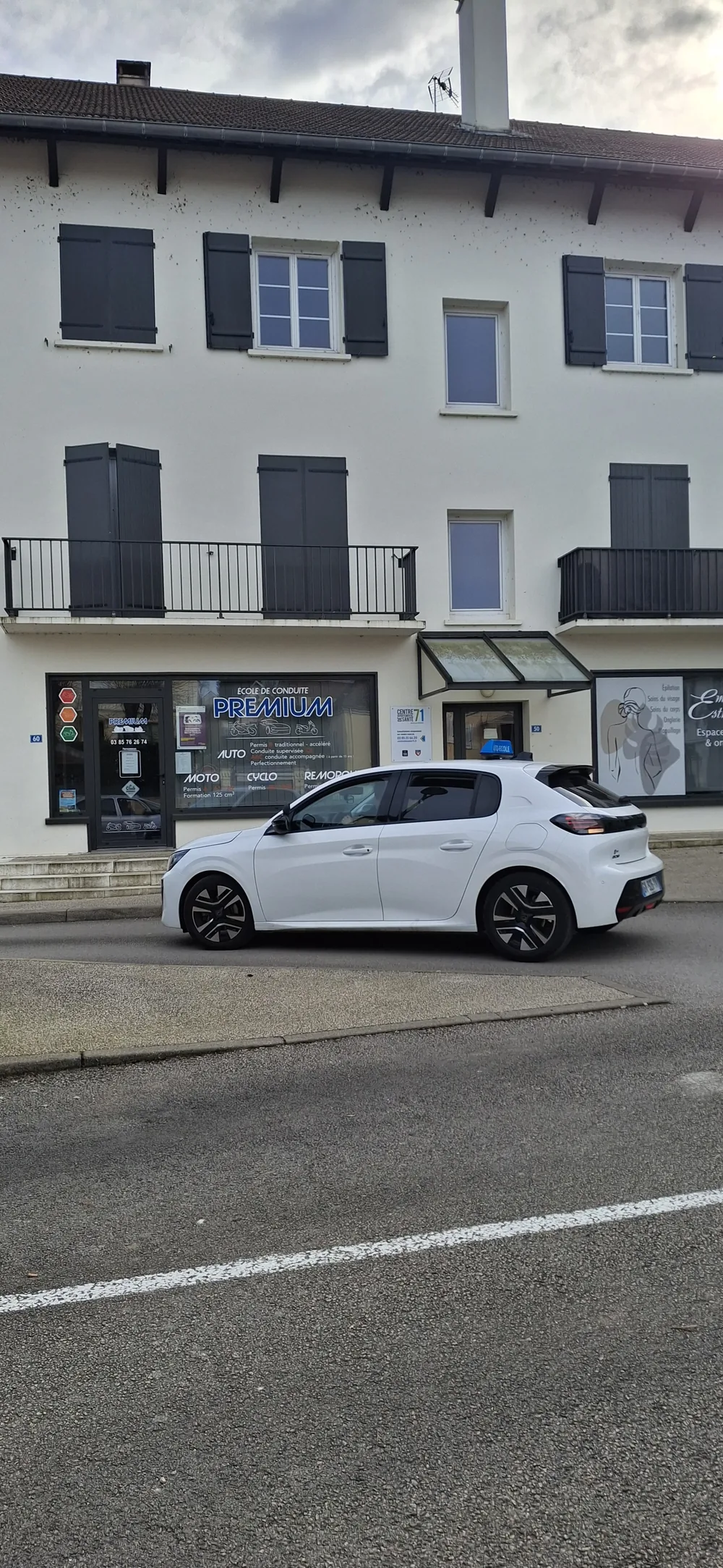 Voiture-école blanche devant l'auto-école Premium IS à Branges